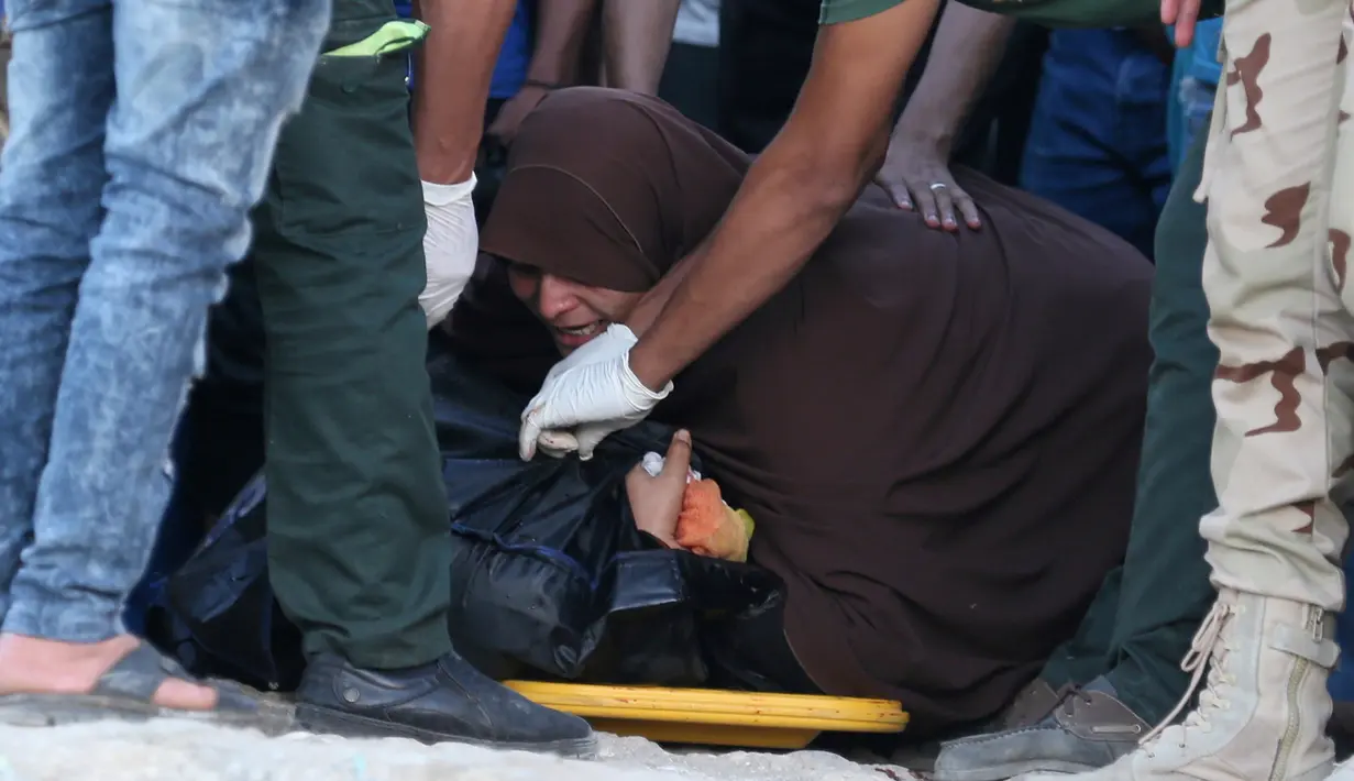 Seorang wanita menangis disamping tubuh anaknya tewas dalam insiden tenggelamnya perahu yang mengangkut ratusan imigran di Al-Beheira, Mesir, (22/9). Setidaknya 52 penumpang ditemukan tewas dan ratusan lainnya masih hilang. (REUTERS/Mohamed Abd El Ghany)