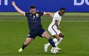 Penyerang Inggris, Raheem Sterling berebut bola dengan pemain Skotlandia, John McGinn pada pertandingan grup D Euro 2020 di stadion Wembley, di London, Jumat (18/6/2021). Skotlandia kini telah mengoleksi satu poin dari dua pertandingan. (Facundo Arrizabalaga/Pool via AP)