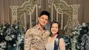 Kevin Kambey hadir mengenakan kemeja batik lengan panjang dan celana panjang warna beige. Sementara sang istri, Thania tampil ayu dengan kebaya kutubaru warna putih dan rok batik sebagai bawahan. [@kkambey].