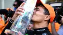 Pembalap McLaren, Lando Norris mencium trofi saat merayakan kemenangan di Formula 1 GP Miami 2024 yang berlangsung di Miami International Autodrome, Miami, Florida, Minggu (05/05/2024). (AFP/Clive Mason)