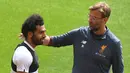 Gelandang Liverpool, Mohamed Salah berbincang dengan pelatih Jurgen Kloop saat latihan di stadion Anfield, Inggris (21/5). Pemain 25 tahun asal Mesir ini merupakan pencetak gol terbanyak tim pada musim ini. (AFP Photo/Paul Ellis)