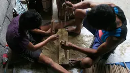 Pekerja membuat tabung pembungkus kembang api di sebuah gubuk, provinsi Bulacan, utara Manila, Rabu (27/12). Seperti banyak negara di Asia, warga Filipina juga akan merayakan malam pergantian tahun dengan kembang api tradisional. (AP/Bullit Marquez)
