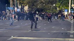 Seorang pengunjuk rasa berkerudung bersiap untuk melemparkan bom molotov ke polisi anti huru hara di luar Parlemen Yunani selama bentrokan di Athena, Yunani, Rabu (9/11/2022). Ribuan pengunjuk rasa berbaris melalui jalan-jalan Athena dan kota Thessaloniki di Yunani utara sebagai pekerja publik dan beberapa sektor swasta meninggalkan pekerjaan untuk pemogokan umum 24 jam terhadap kenaikan harga.  (AP Photo/Petros Giannakouris)