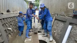 Pekerja dari Suku Dinas Sumber Daya Air (Sudin SDA) sedang menutup sumur resapan di Karet Pasar Baru, Jakarta Pusat, Jumat (18/12/2020). Rencananya Pemerintah Jakarta Pusat akan membangun 400 sumur resapan dapat meminimalisir genangan dan banjir. (merdeka.com/Dwi Narwoko)