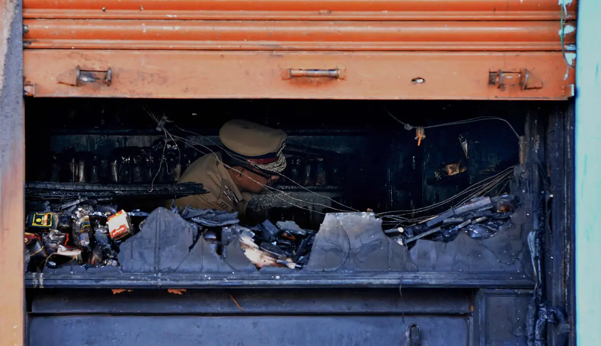 Seorang perwira polisi India mengecek restoran yang terbakar di Bangalore (8/1). Polisi mengatakan sebuah arus listrik pendek yang menyebabkan kebakaran di Kailash Bar & Restoran di pusat teknologi selatan Bangalore. (AFP Photo/Manjunath Kiran)