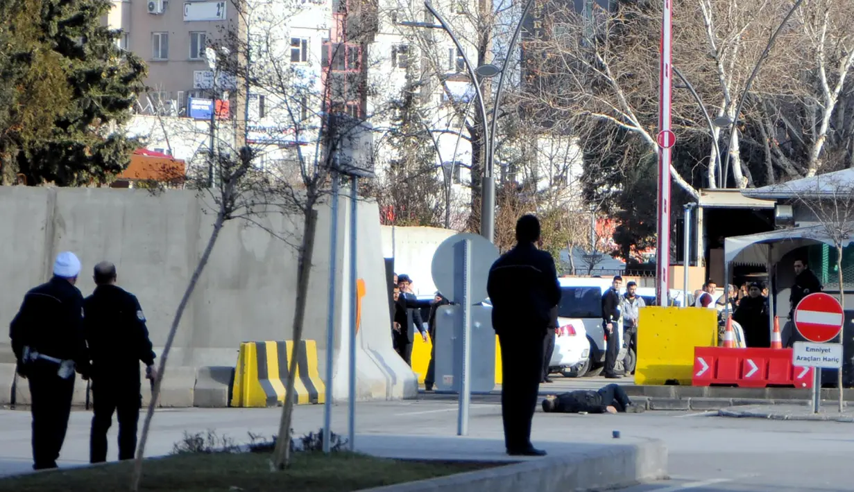 Petugas kepolisian mendekati seorang pria yang tergeletak di tanah, di luar kantor polisi di Gaziantep, Selasa (10/1). Seorang perwira polisi terluka ringan akibat penyerangan yang dilakukan pria tersebut bersama rekannya yang kabur. (AFP PHOTO/STR)