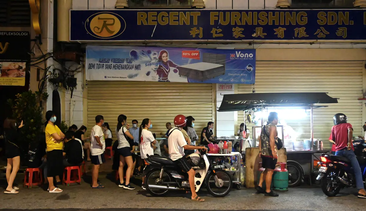 Pelanggan menunggu untuk membeli makanan di warung jajanan populer di Penang (1/8/2020). Malaysia tengah memperingatkan gelombang kedua virus corona COVID-19. (AFP Photo/Goh Chai Hin)