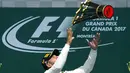 Lewis Hamilton melempar trofi juara setelah menang  pada ajang Formula One Canadian Grand Prix di Montreal, Canada, (11/6/2017).  (Paul Chiasson/The Canadian Press via AP)