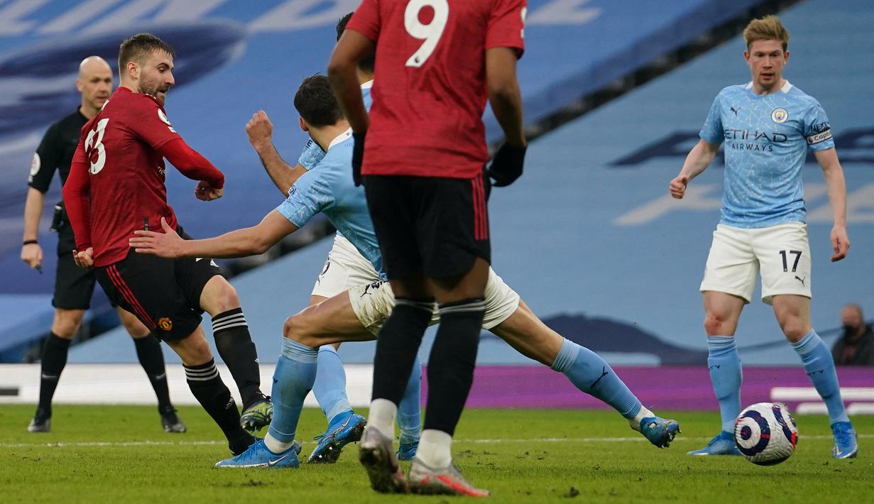 Bek Manchester United, Luke Shaw (kiri) melepaskan tendangan yang berbuah gol kedua timnya ke gawang Manchester City dalam laga lanjutan Liga Inggris 2020/21 di Etihad Stadium, Minggu (7/3/2021). MU menang 2-0 atas Mancity. (AFP/Dave Thompson/Pool)