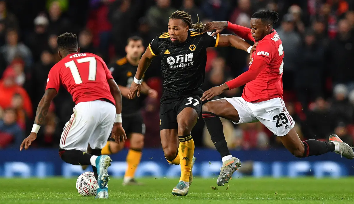 Pemain Wolverhampton Wanderers Adama Traore (tengah) mencoba melewati pemain Manchester United Fred (kiri) dan Aaron Wan-Bissaka pada putaran ketiga Piala FA di Old Trafford, Manchester, Inggris, Rabu (15/1/2020). Manchester United menang 1-0. (PAUL ELLIS/AFP)