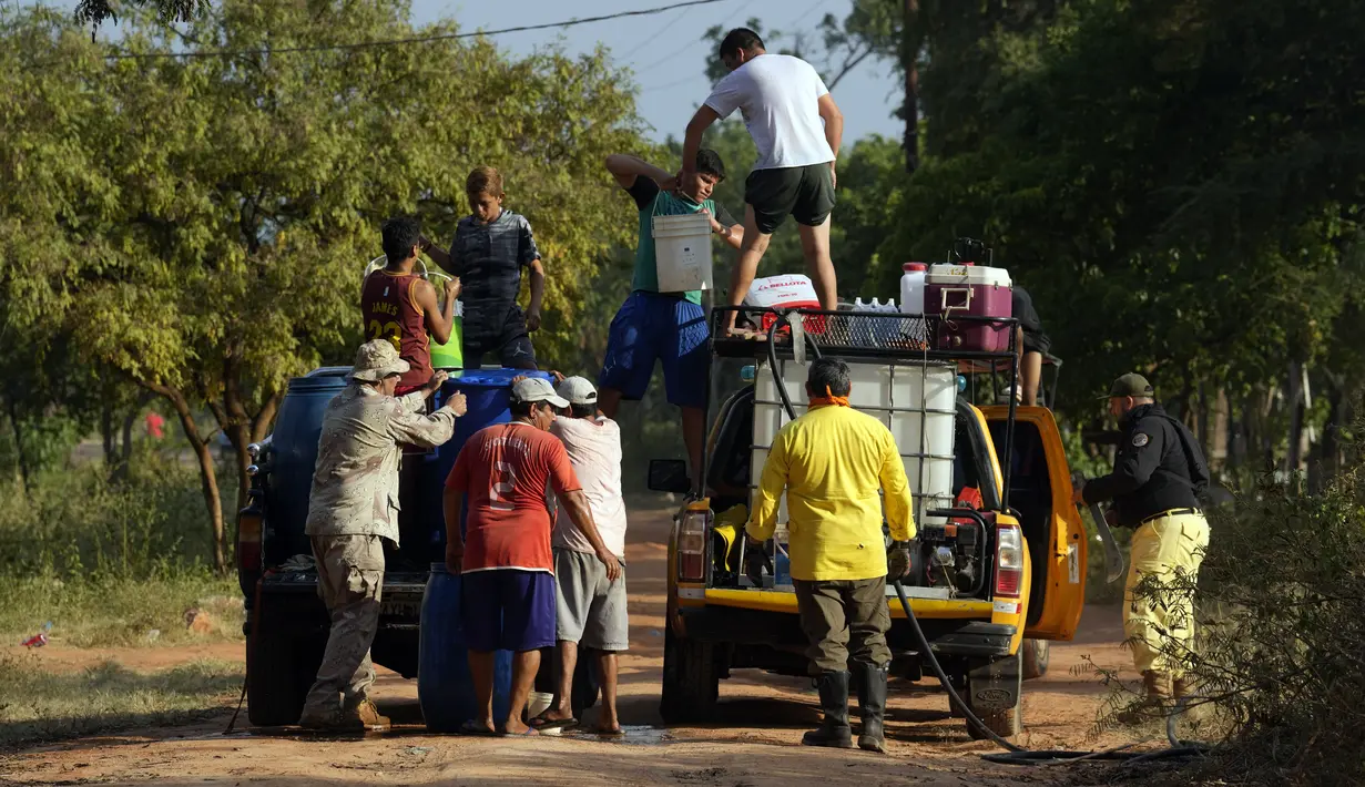 Warga membantu petugas pemadam kebakaran selama kebakaran di lingkungan Banco San Miguel di Asuncion, Paraguay (18/1/2022). Cuaca kering yang tidak biasa memicu kebakaran di lapangan terbuka, peternakan pribadi, dan lahan publik sekitar kota. (AP Photo/Jorge Saenz)