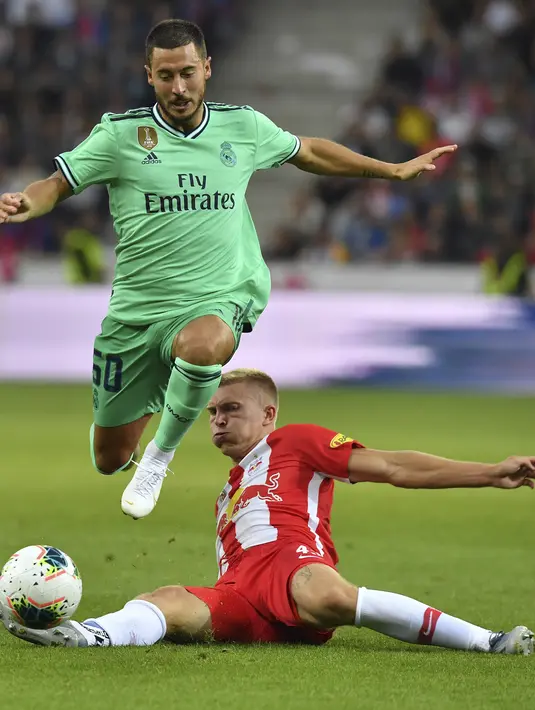 Gelandang Real Madrid, Eden Hazard berusaha melewati pemain Red Bull Salzburg, Rasmus Kristensen selama pertandingan persahabatan di Red Bull Arena, Austria (8/8/2019). Winger asal Belgia itu mencetak gol perdananya untuk klub barunya Real Madrid. (AP Photo/Kerstin Joensson)