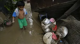 Seorang anak berjalan di sepanjang perairan berlumpur akibat Topan Rai di desa mereka di kota Talisay, provinsi Cebu, Filipina tengah, Jumat (17/12/2021). Topan mengakibatkan banjir sehingga menjebak penduduk di atap, menumbangkan pohon, dan memutus aliran listrik. (AP Photo/Jay Labra)