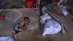 Seorang anak Rohingya tidur di rumah darurat di Kamp Pengungsi Kutupalong di Cox's Bazar, Bangladesh, Senin (22/7/2019). Lebih dari satu juta etnis Rohingya melarikan diri dari Myanmar dan menetap di Kutupalong yang merupakan salah satu kamp pengungsi terbesar di dunia. (MUNIR UZ ZAMAN/AFP)