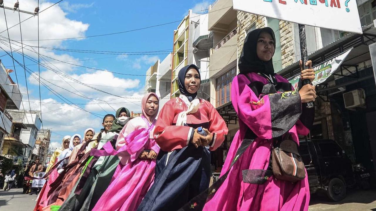 Sebuah foto yang diambil pada 14 Oktober 2023 menampilkan para peserta dengan pakaian adat Korea memegang papan petunjuk dengan tulisan Hangeul atau aksara Korea dalam sebuah parade untuk merayakan HUT Kota Baubau, Pulau Buton, Sulawesi Tenggara.