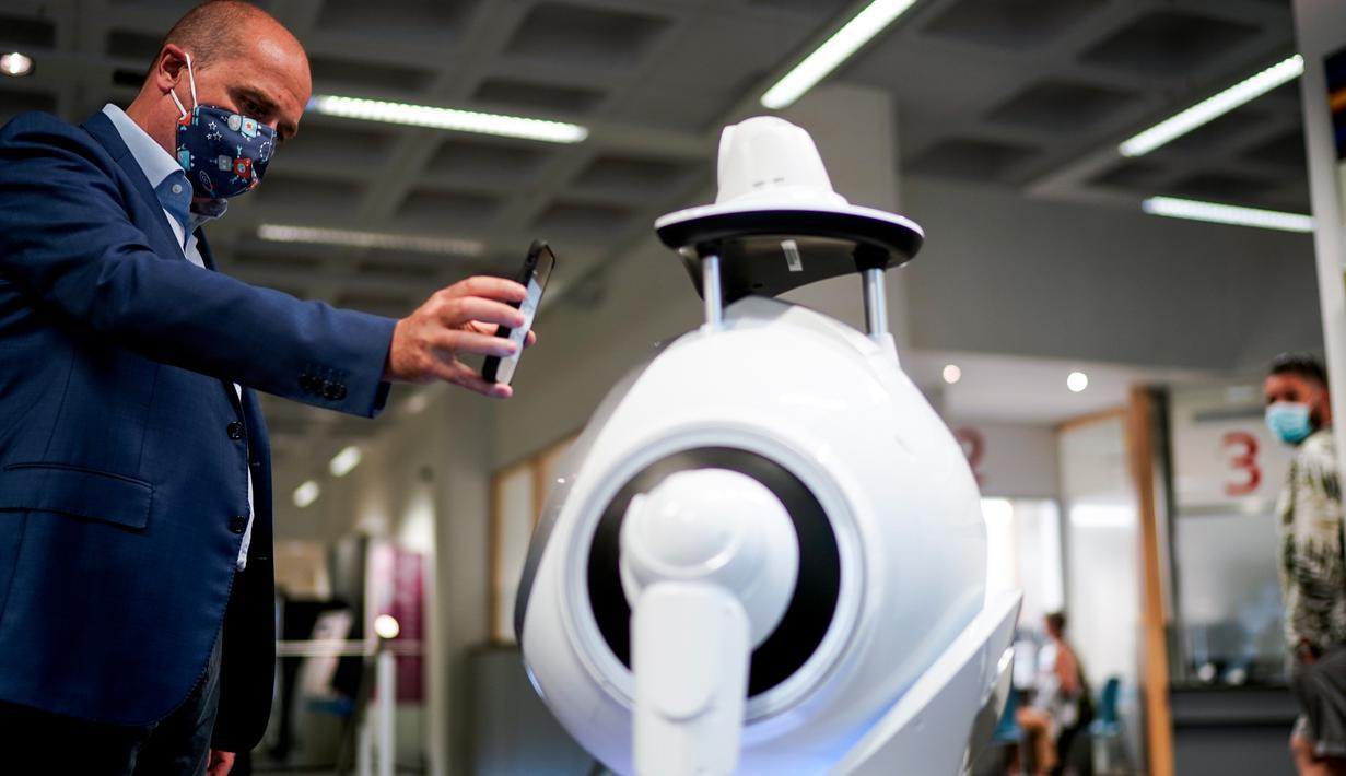 Seorang karyawan perusahaan Belgia, ZoraBots, menguji robot yang disebut CRUZR di Antwerp University Hospital (UZA) pada 29 Mei 2020. Robot ini dapat mendeteksi demam serta mengetahui pengunjung rumah sakit  yang memakai Masker atau tidak. (Kenzo TRIBOUILLARD/AFP)