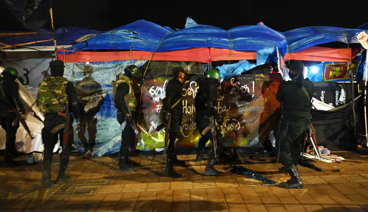 Anggota pasukan keamanan Sri Lanka membongkar bangunan sementara yang didirikan oleh pengunjuk rasa anti-pemerintah di lokasi kamp protes di depan Sekretariat Presiden di Kolombo, Jumat (22/7/2022). Pasukan keamanan menggunakan pengeras suara meminta beberapa ratus pengunjuk rasa untuk mundur dan membatasi diri ke area yang ditentukan di dekat sekretariat. (Arun SANKAR / AFP)