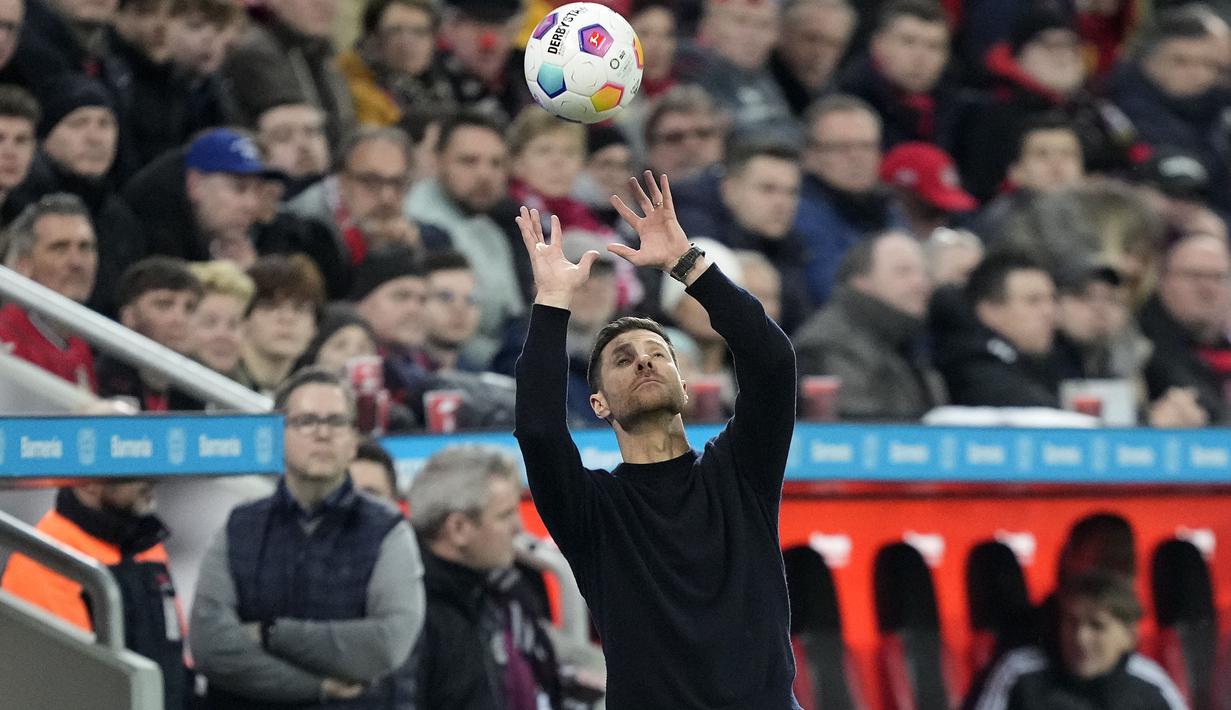 Pelatih Bayer Leverkusen, Xabi Alonso menangkap bola yang keluar dari lapangan saat laga lanjutan Bundesliga 2023/2024 melawan Bayern Munchen di BayArena, Leverkusen, Jerman, Minggu (11/02/2024) WIB. (AP Photo/Martin Meissner)