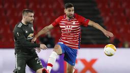 Gelandang Granada, Antonio Puertas (kanan) menguasai bola dibayangi bek Manchester United, Luke Shaw dalam laga leg pertama perempatfinal Liga Europa 2020/2021 di Nuevo Los Carmenes Stadium, Granada, Kamis (8/4/2021). Granada kalah 0-2 dari Manchester United. (AP/Fermin Rodriguez)