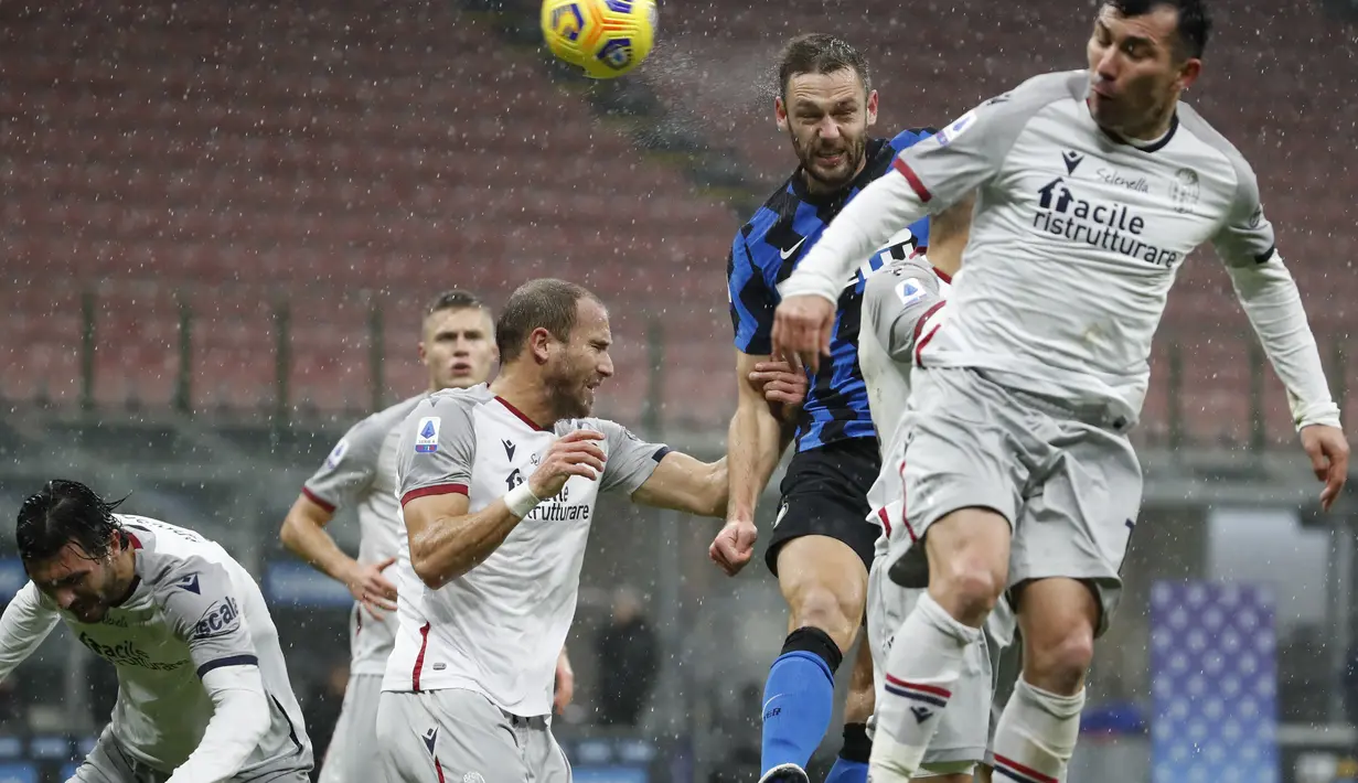 Gelandang Bologna, Gary Medel (kanan) menyundul bola dari kawalan bek Inter Milan, Stefan de Vrij (tengah) pada pertandingan lanjutan Liga Serie A Italia di Stadion San Siro Milan, Minggu (6/12/2020). Inter menang 3-1 atas Bologna. (AP Photo/Antonio Calanni)