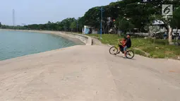 Anak-anak bermain sepeda di Waduk Cincin, Jakarta, Selasa (8/1). Pemerintah Kota Administratif Jakarta Utara berencana menata kawasan Hutan Kota Waduk Cincin yang berlokasi di kawasan Sunter, Jakarta Utara. (Liputan6.com/Herman Zakharia)