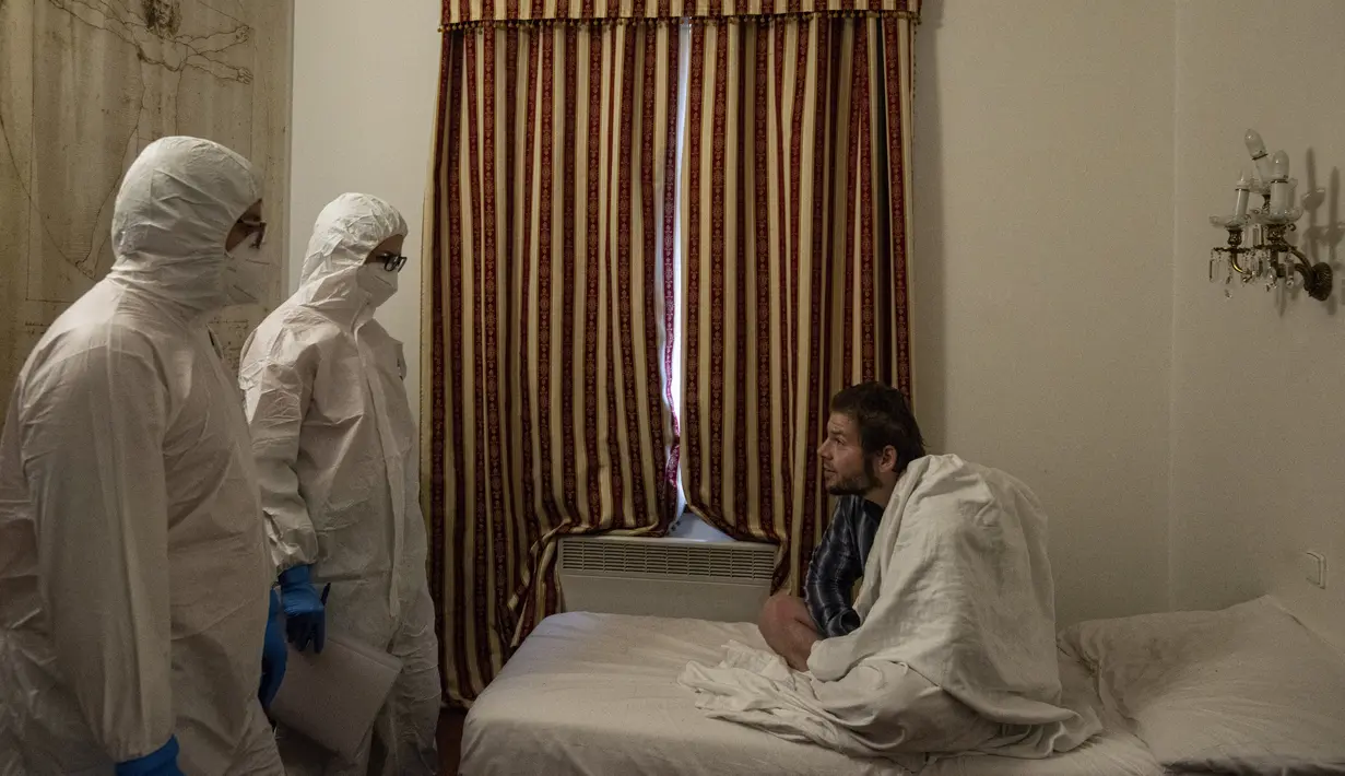 Petugas kesehatan dengan alat pelindung diri (APD) berbincang dengan tunawisma pasien virus corona di sebuah kamar hotel di Praha, Senin (8/3/2021). Di hotel berbintang empat King Charles Boutique, paramedis merawat dan memberikan obat kepada para tunawisma yang terpapar Covid-19. (MICHAL CIZEK/AFP)