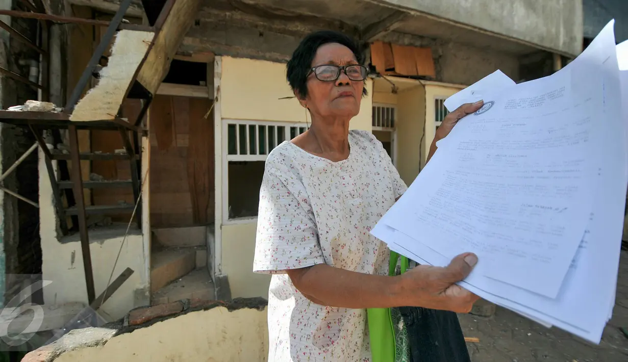 Seorang ibu penguni rumah menunjukan surat Hak Guna Bangunan ketika petugas melakukan penertiban terhadap rumah miliknya, tepat di samping Kantor Kelurahan Rawajati, Pancoran, Jakarta, Selasa (22/12). (Liputan6.com/Yoppy Renato)