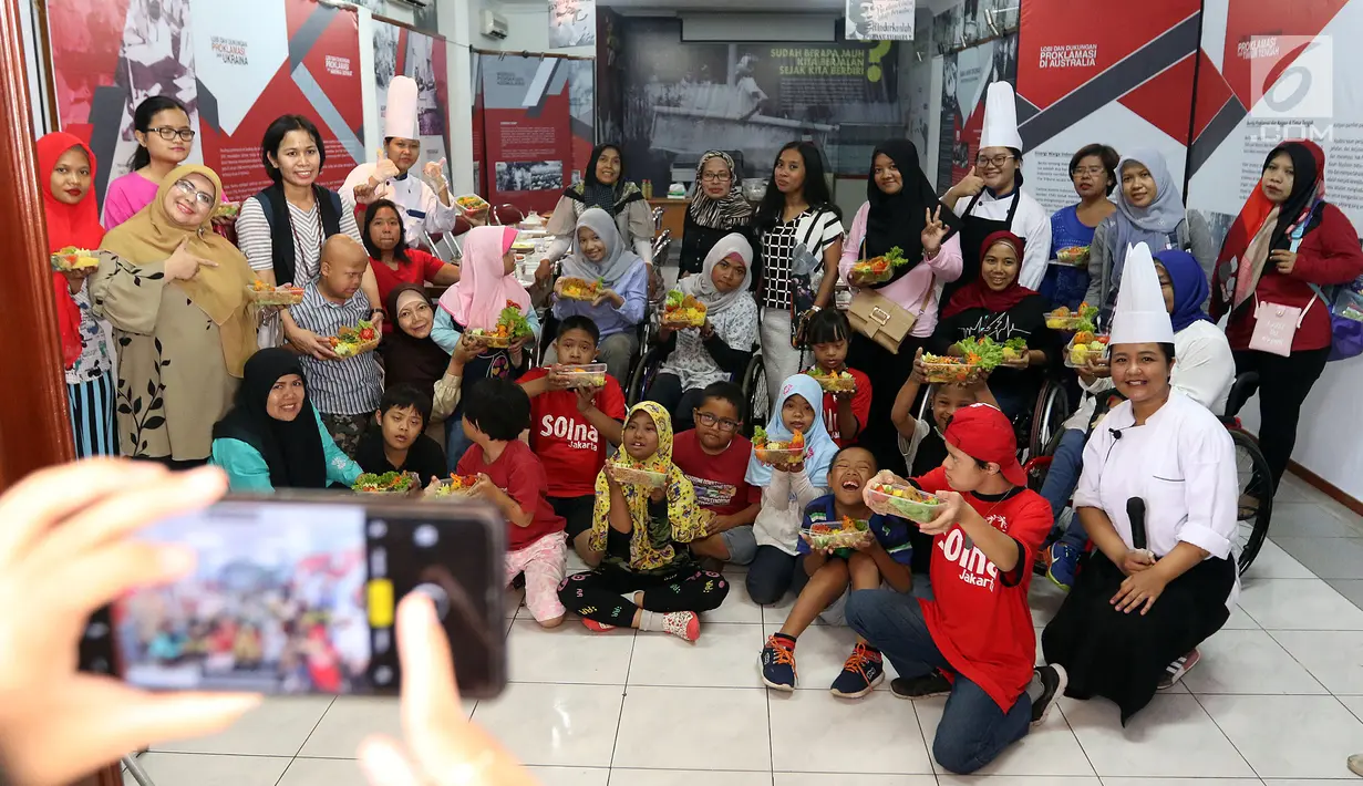 Komunitas penyandang disabilitas, down syndrome, dan rungu wicara berpose untu foto saat mengikuti program kreativitas menghias Bekal Nusantara di Museum Naskah Proklamasi, Jakarta, Sabtu (14/9/2019). Mereka membuat makanan menggunakan bahan-bahan khas Indonesia. (Liputan6.com/JohanTallo)