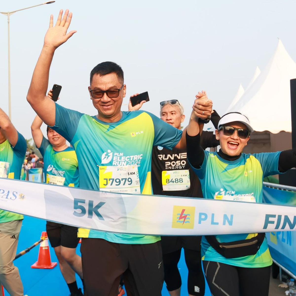Direktur Utama PLN, Darmawan Prasodjo (kiri) bersama istri, Diny Darmawan Prasodjo (kanan) saat melintasi garis finish dan menyelesaikan PLN Electric Run 2024 kategori 5K