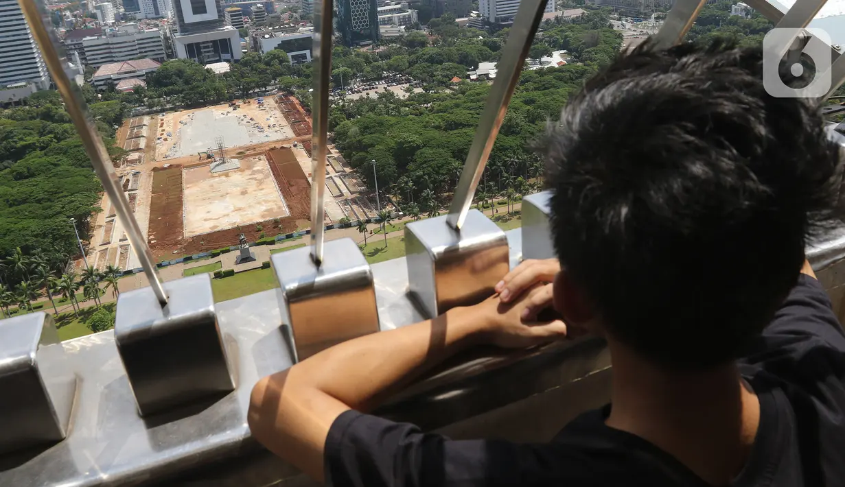 Seorang anak melihat proyek revitalisasi  taman sisi selatan Monunem Nasional, Jakarta, Rabu (29/1/2020). Berdasarkan hasil rapat koordinasi bersama DPRD DKI Jakarta, Sekda DKI Jakarta Saefullah memutuskan menghentikan sementara proyek revitalisasi kawasan Monas. (Liputan6.com/Herman Zakharia)