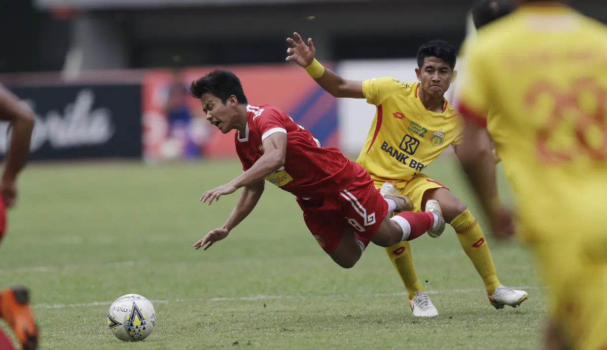 Gelandang Perseru Badak Lampung FC, Hariyanto Panto,terjatuh saat berebut bola dengan bek Bhayangkara FC, I Putu Gede, pada laga Liga 1 2019 di Stadion Patriot, Bekasi, Jumat (16/8). Bhayangkara FC takluk 0-1 dari Badak Lampung FC. (Bola.com/M Iqbal Ichsan)
