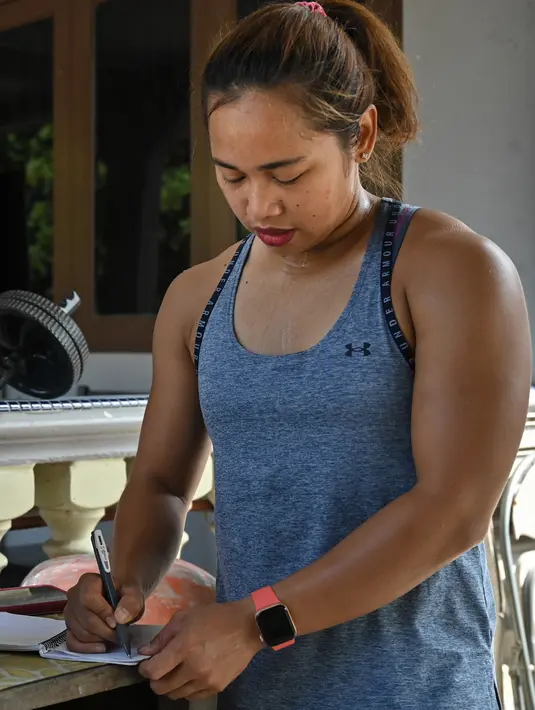Atlet angkat besi Olimpiade Filipina, Hidilyn Diaz menulis catatan selama sesi latihan di Jasin, kota Malaka, pada 21 Mei 2021. Diaz yang terpaksa tinggal di Malaysia bertekad situasi tidak akan menghalangi cita-citanya menjadi peraih medali emas Olimpiade pertama dari Filipina (Mohd RASFAN/AFP)
