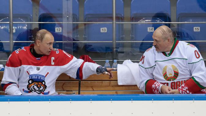Presiden Rusia Vladimir Putin (kiri) dan Presiden Belarus Alexander Lukashenko (kanan) berbincang disela-sela pertandingan hoki es di Shayba Arena, Resor Laut Hitam Sochi, Rusia, (15/2). (Sergei Chirikov / Pool / AFP)