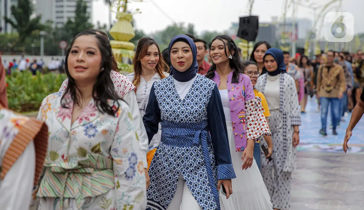 Sejumlah orang yang mengenakan batik berjalan di catwalk sepanjang Jalan Jenderal Sudirman, Jakarta, Minggu (2/10/2022). Kegiatan yang diikuti ratusan orang ini diselenggarakan oleh Bank Mandiri untuk menyambut Hari Batik Nasional yang jatuh setiap tanggal 2 Oktober 2022. (Liputan6.com/Faizal Fanani)