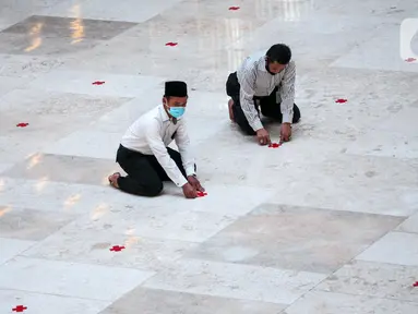 Petugas memasang tanda silang antar saf di Masjid Istiqlal, Jakarta Pusat, Selasa (2/6/2020). Masjid Istiqlal merupakan salah satu sarana ibadah yang dipersiapkan menerapkan prosedur standar new normal atau kenormalan baru. (Liputan6.com/Faizal Fanani)