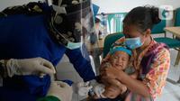 Perawat dibantu kader Posyandu menyuntikan vaksin campak, vaksin pentabio berisi vaksin DPT, Hepatitis B dan Haemophilus Influenzae dan Imunisasi Polio terhadap anak di RW 09, Kelurahan Pondok Benda, Tangerang Selatan, Senin (14/12/2020). (merdeka.com/Dwi Narwoko)
