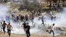 Pengunjuk rasa Palestina menghindari gas air mata yang ditembakkan tentara Israel saat memprotes pencaplokan tanah untuk perluasan permukiman Yahudi di dekat desa Beit Dajan, timur Nablus, Palestina (9/10/2020). (AFP/Jaafar Ashtiyeh)