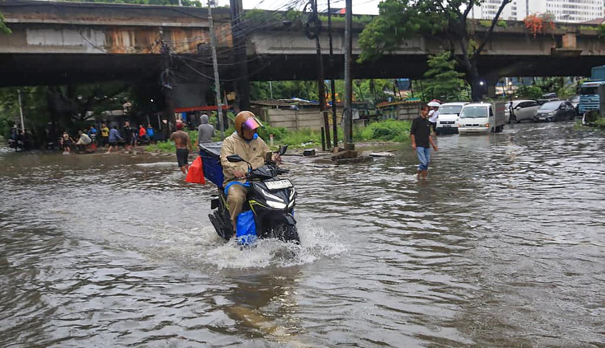 Kondisi ini mengakibatkan perlambatan arus lalu lintas dan menyulitkan mobilitas warga, terutama pada jam-jam sibuk. Tampak dalam foto, pengendara melintasi banjir yang menggenangi Jalan Jembatan Tiga Raya, Jakarta Utara, Senin (12/1/2026). (merdeka.com/Arie Basuki)