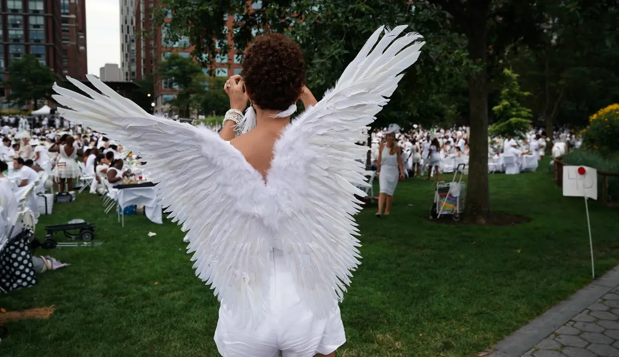 Seorang wanita dengan mengenakan sayap menghadiri Diner en blanc di Rockefeller Park, New York, Rabu (17/7/2019). New York City Diner en Blanc adalah sebuah pesta makan malam rahasia dengan pakaian bernuansa putih yang diadopsi dari budaya Prancis. (TIMOTHY A. CLARY / AFP)