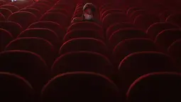 Seorang perempuan memakai masker saat dia menunggu untuk menonton film di dalam aula bioskop Beltrade, di Milan, Senin (26/4/2021). Italia kembali dibuka secara bertahap pada hari Senin setelah enam bulan memberlakukan lockdown untuk menghambat penyebaran Covid-19. (AP Photo/Antonio Calanni)