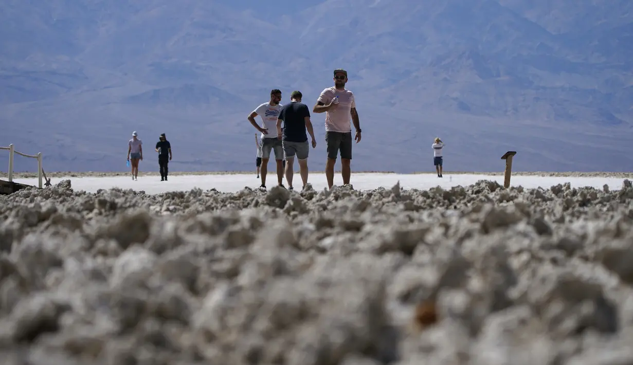 Orang-orang mengunjungi dataran garam di Badwater Basin, di Taman Nasional Death Valley, Taman Nasional Death Valley, California, Kamis (1/9/2022). Kondisi yang terlalu panas ini bisa menyebabkan manusia mengalami dehidrasi dan merusak kendaraan bermotor yang melintas.  (AP Photo/John Locher)