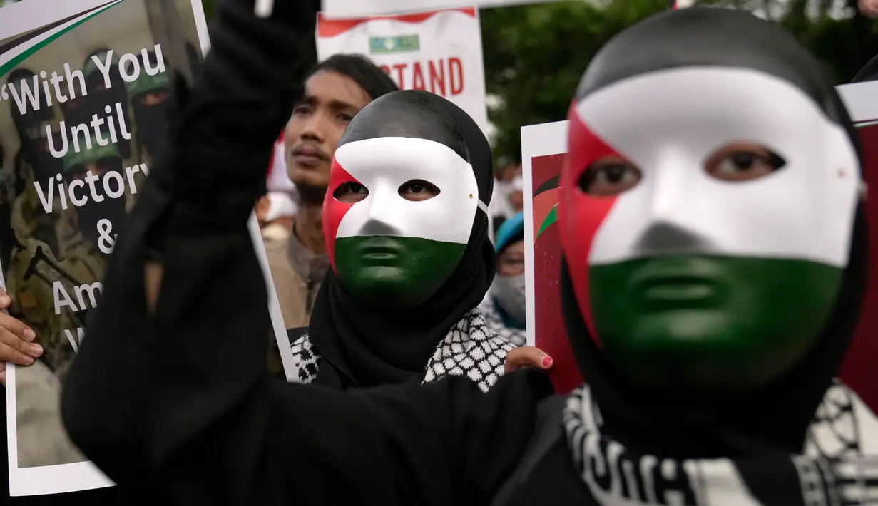 Para pengunjuk rasa yang mengenakan topeng dengan warna bendera Palestina memegang poster dalam aksi unjuk rasa untuk mendukung Palestina di luar Kedutaan Besar Amerika Serikat di Jakarta, Sabtu 13 Januari 2024. (AP Photo/Dita Alangkara)