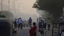 Orang-orang berjalan melintasi saat api besar melalap tempat pembuangan sampah Ghazipur di New Delhi, India (28/3/2022). Kebakaran besar terjadi di tempat pembuangan sampah di daerah Ghazipur Delhi timur yang menyebabkan kepulan asap besar menyelimuti wilayah tersebut. (AP Photo/Manish Swarup)