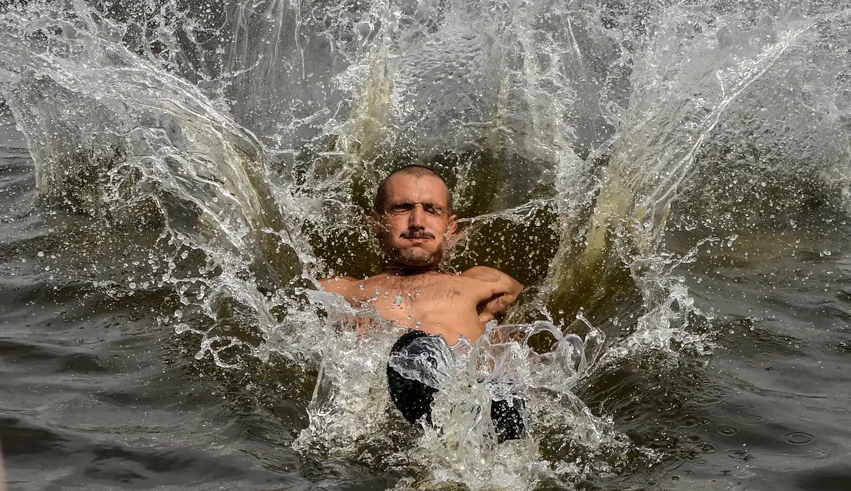 Seorang pria Pakistan mendinginkan diri ke perairan Laut Arab saat musim panas di Karachi pada 5 Juli 2020. Mereka menghabiskan hari yang cerah dengan berenang di tengah pandemi virus corona. (Photo by Rizwan TABASSUM / AFP)