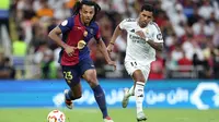 Bek Barcelona asal Prancis Jules Kounde berlari membawa bola melewati penyerang Real Madrid asal Brasil Rodrygo selama pertandingan final Piala Super Spanyol antara Real Madrid dan Barcelona di King Abdullah Sport City di Jeddah pada 12 Januari 2025.Haitham AL-SHUKAIRI / AFP