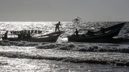 Seorang nelayan Palestina melempar tali dari perahu ke perahu lain saat menangkap ikan di Laut Mediterania, Rafah, Jalur Gaza, Rabu (2/9/2020). (SAID KHATIB/AFP)