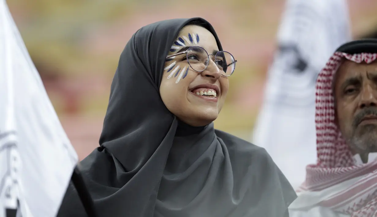 Seorang fans perempuan tersenyum saat menunggu pertandingan antara Valencia dan Real Madrid pada semifinal Piala Super Spanyol King Abdullah Sport City di kota pelabuhan Arab Saudi, Jeddah (8/1/2020). (AP Photo/Hassan Ammar)