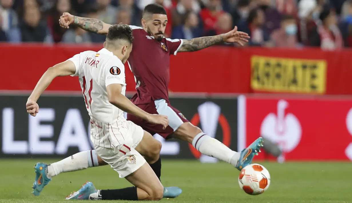 Gelandang Sevilla, Ivan Rakitic berebut bola dengan pemain West Ham, Manuel Lanzini pada pertandingan leg pertama babak 16 besar Liga Europa di stadion Ramon Sanchez-Pizjuan, Spanyol, Jumat (11/3/2022). Sevilla menang atas West Ham 1-0. (AP Photo/Angel Fernandez)