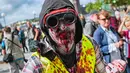 Seorang pria menggunakan kostum seperti zombie berjalan di tengah kota dalam parade "Zombie Walk" di Stockholm, Swedia, Sabtu (19/8). Zombie Walk adalah acara yang rutin dilakukan saat musim panas tiba, tepatnya akhir Agustus. (Jonathan NACKSTRAND/AFP)