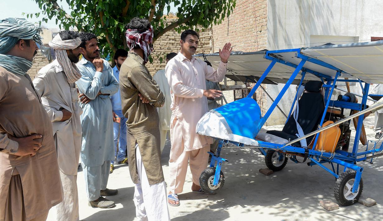 Muhammad Fayyaz berbincang dengan warga yang melihat pesawat buatannya di Desa Tabur, Provinsi Punjab, Pakistan, 8 April 2019. Karya lelaki berusia 32 tahun tersebut berhasil menarik perhatian Angkatan Udara Pakistan. (ARIF ALI/AFP)